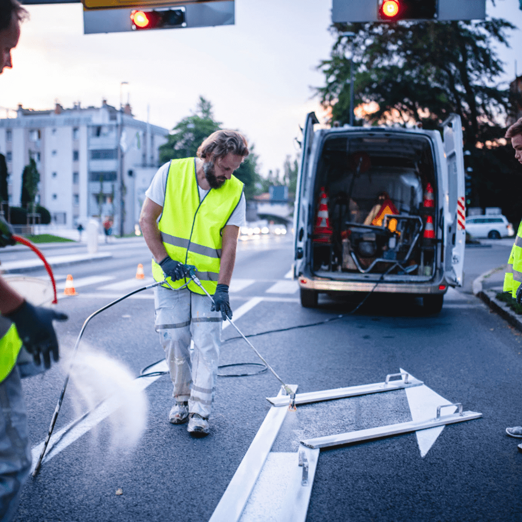 Workers painting road arrows at night.